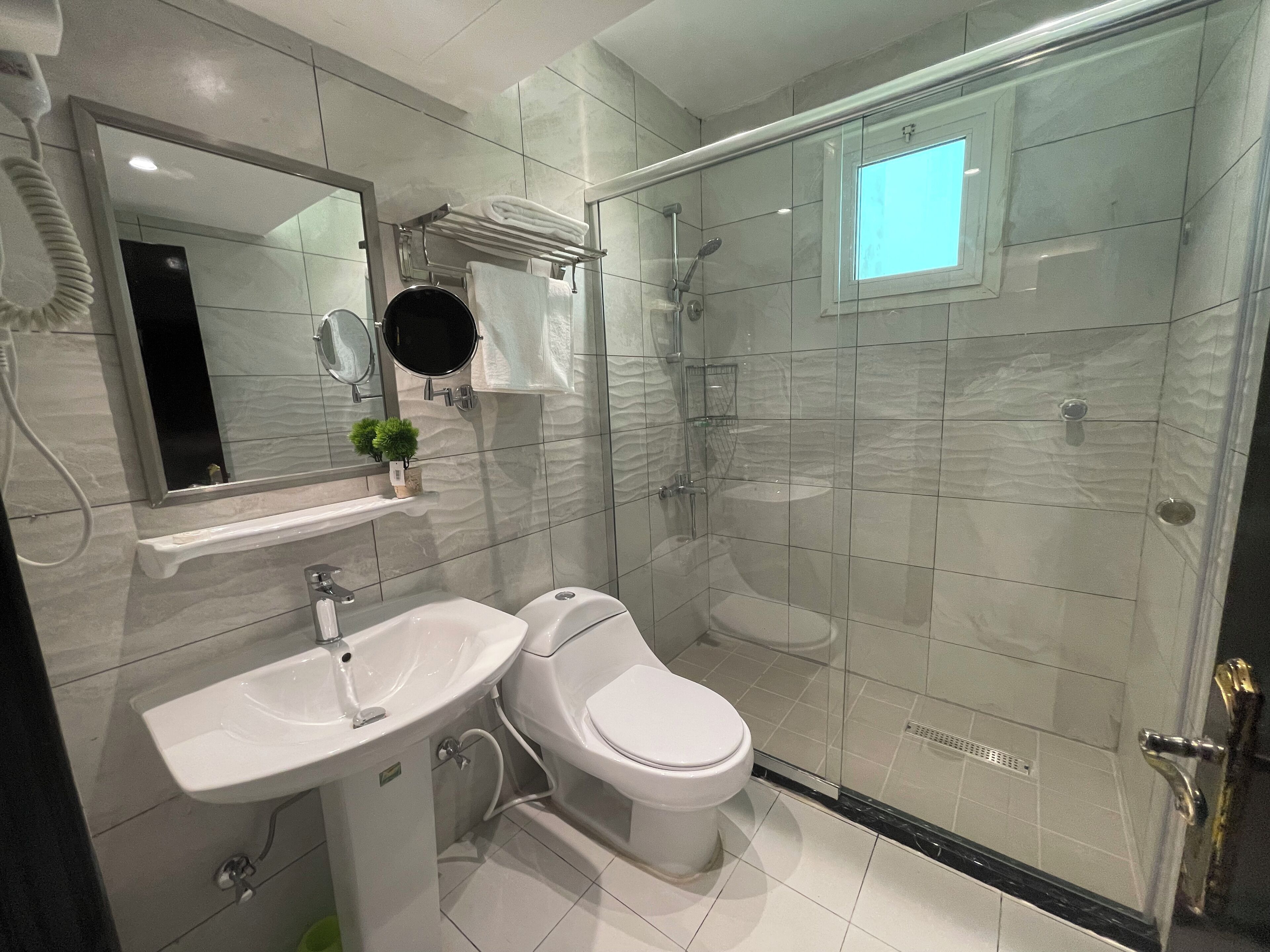Un baño moderno con ducha de vidrio, un lavamanos blanco y un inodoro.