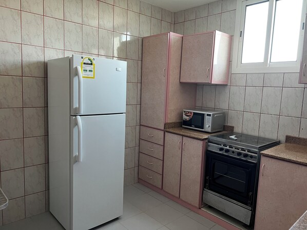 Una cocina compacta con un refrigerador blanco, un microondas y una estufa.