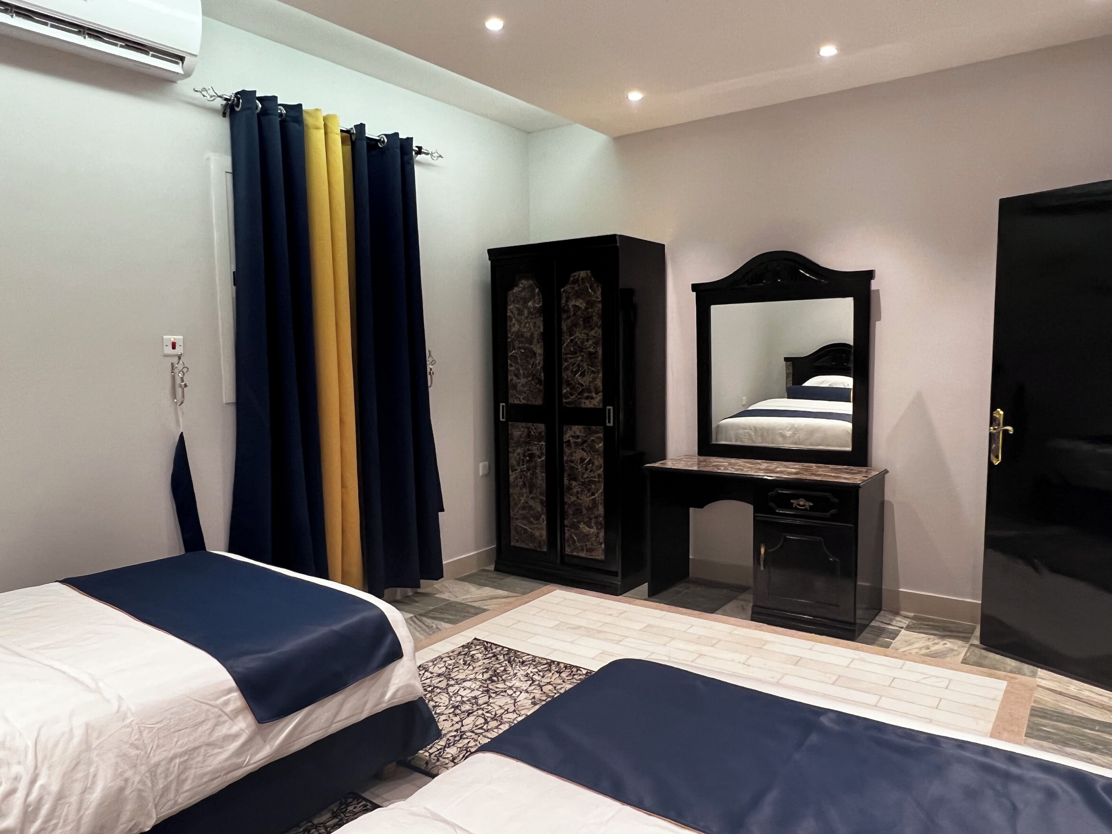 Een slaapkamer met twee bedden, een dressoir, een spiegel en een kledingkast.