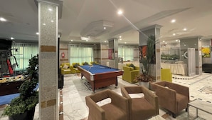 A well-lit indoor space with a pool table, multiple sofas, and a fitness machine. - golden comfort (Hafr Al Batin)