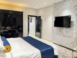 Una habitación de hotel con una cama grande, un televisor montado en la pared y un armario.