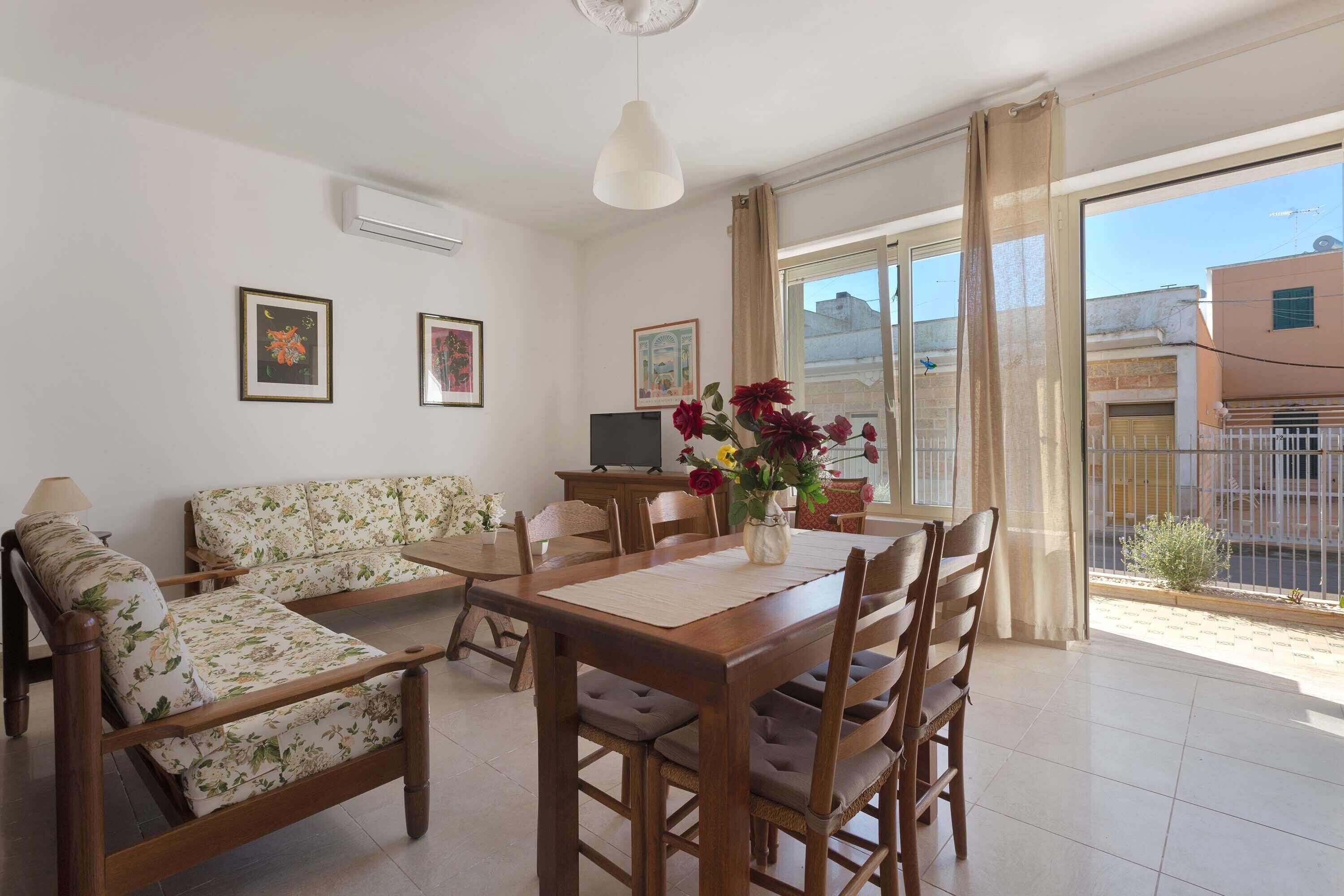 A spacious living room with a wooden dining table, two sofas, and a TV.