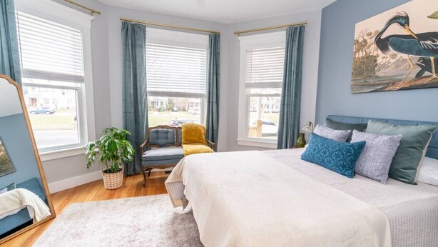A bedroom with a large bed, a chair, a desk, and a window with curtains. - Edgewood: Close to Yale, Hospital & Park (New Haven)