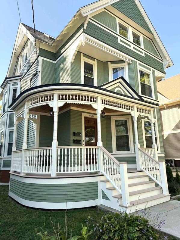 A two-story house with a wrap-around porch and a front entrance.