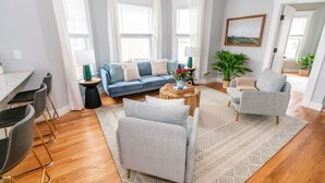 A modern living room with a sofa, chairs, a coffee table, and a dining area with chairs and a table. - Edgewood: Close to Yale, Hospital & Park (New Haven)