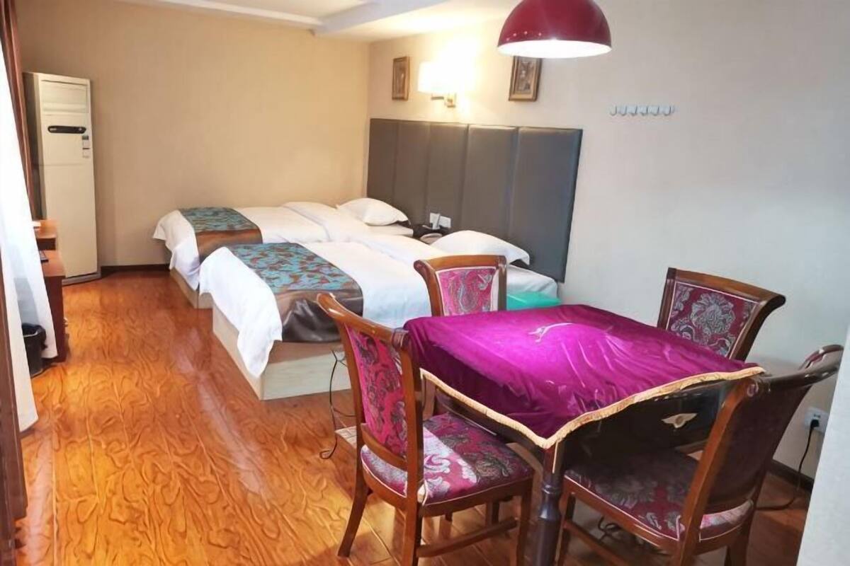 A hotel room with a bed, two chairs, a table, and a desk.