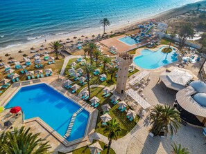 An aerial view of a resort with multiple swimming pools, sun loungers, and umbrellas.