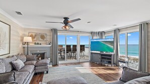Ein großzügiges Wohnzimmer mit großem Fernseher, Kamin und Meerblick.