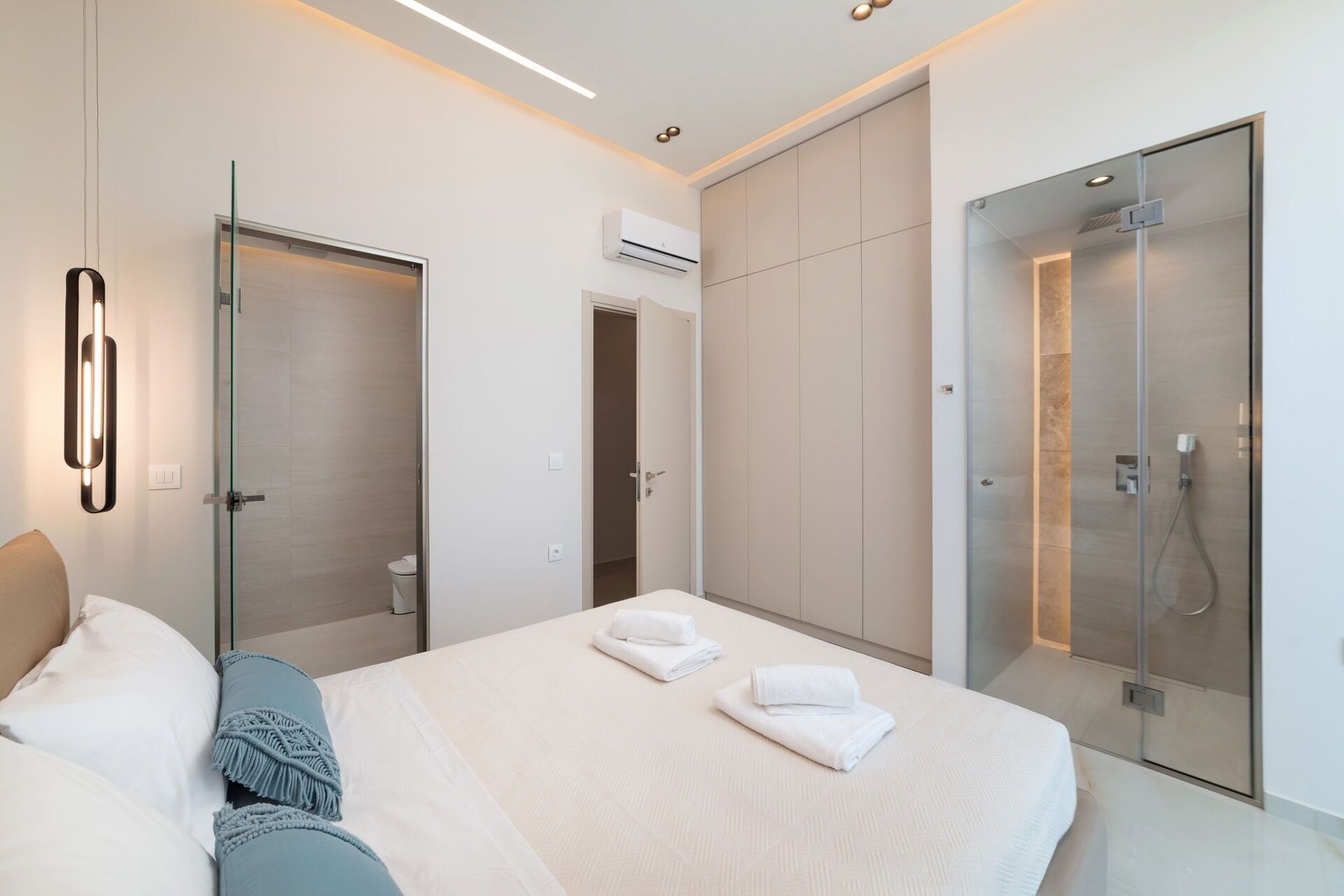 Une chambre d’hôtel moderne dotée d’un grand lit, d’une douche à parois de verre et d’un design minimaliste.