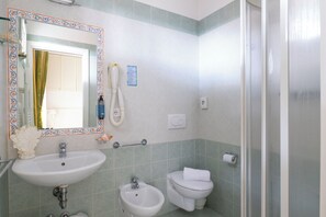A bathroom with a sink, bidet, toilet, and a mirror with a decorative frame. - Hotel Negresco (Riccione)