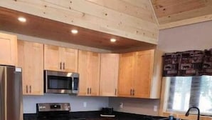 Een moderne keuken met houten kastjes, roestvrijstalen apparatuur en een centraal eiland met stoelen.