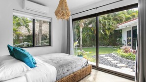 Un dormitorio con cama, un ventanal y vistas a un jardín.