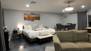 Ein modernes Hotelzimmer mit einem Bett, einer Couch, einem Esstisch mit Stühlen und einem Deckenventilator.