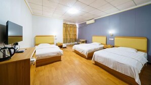 Une chambre d’hôtel avec deux lits, un bureau avec un ordinateur et une télévision.