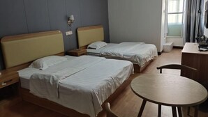 Une chambre d’hôtel avec deux lits, une table ronde, un bureau et une fenêtre avec des rideaux.
