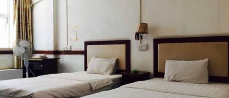 Habitación de hotel con dos camas, una mesita de noche, una lámpara y un equipo de aire acondicionado.