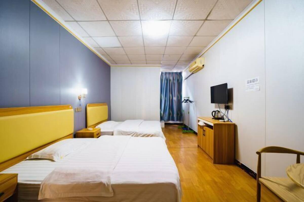 A hotel room with two beds, a desk, a chair, a television, and a curtain.