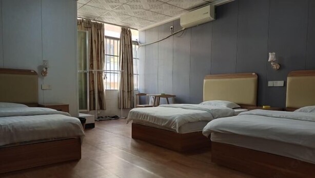 Une chambre d’hôtel avec deux lits simples, une petite table et une fenêtre avec des rideaux.