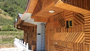 A wooden cabin with a sloped roof, a small window, and a white door. - Qianxi Hotel (Deqin)