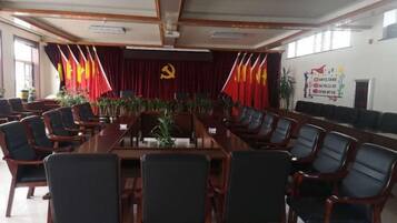Een congreszaal met een lange tafel en stoelen, een spreekgestalte en een achtergrond met vlaggen en een hamer en sikkel embleem.