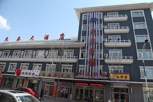 Un hotel de varios pisos con fachada tradicional, múltiples balcones y señalización para diferentes comercios.