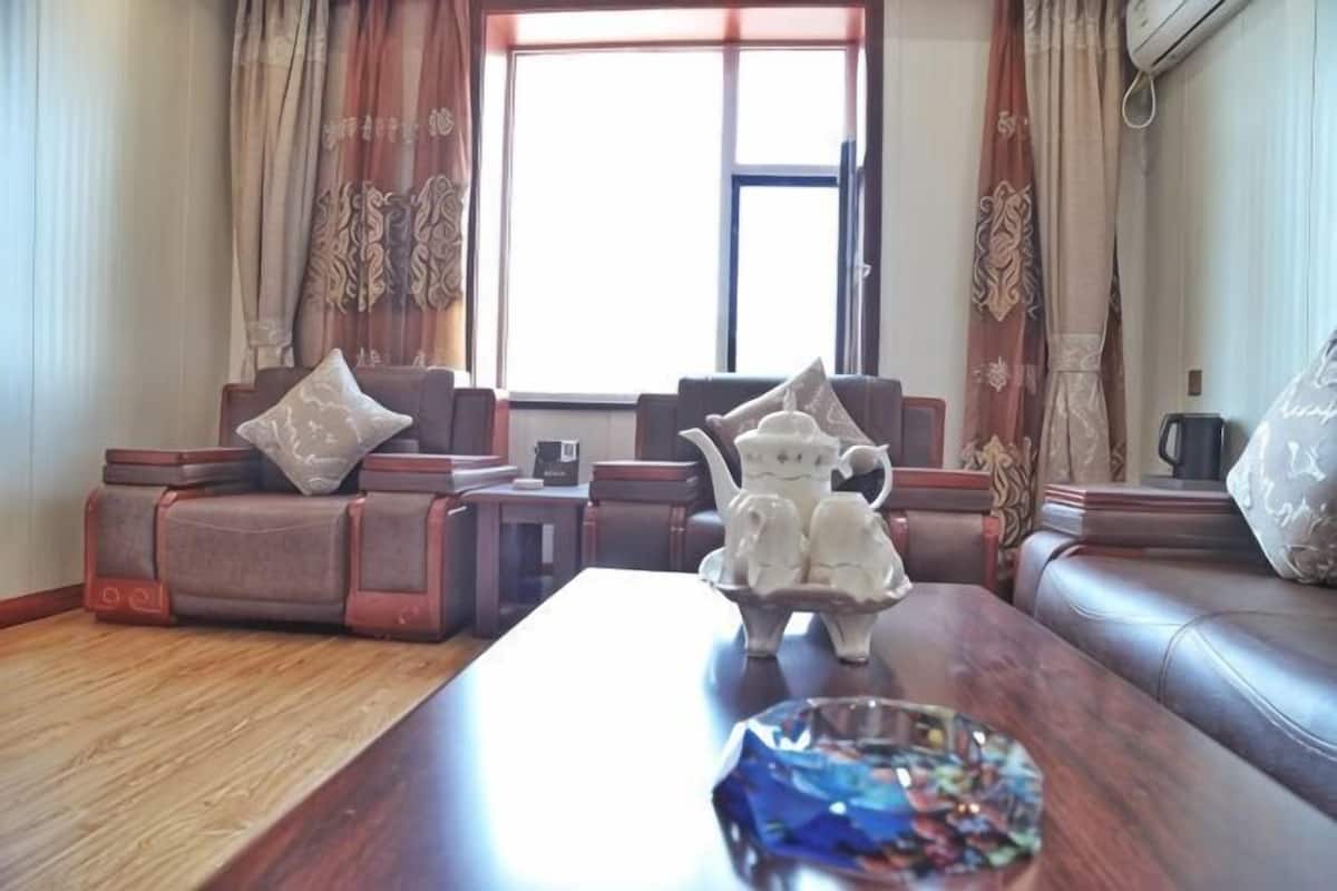 A living room with a sofa, a coffee table, and a window with curtains.