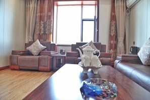 Una sala de estar con sofá, mesa de centro y ventana con cortinas.