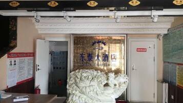 A hotel entrance with a lion statue, a reception desk, and a door with a sign.