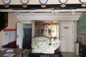 Entrada de hotel con una estatua de león, una recepción y una puerta con un cartel.