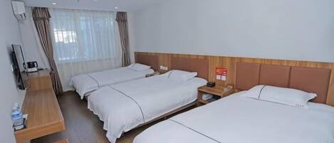 A hotel room with three beds, a desk, and a television.
