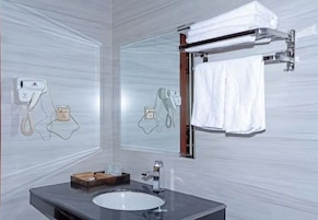 Une salle de bain avec un lavabo rond, un porte-serviettes et un miroir.