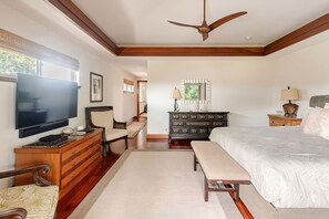 Une chambre à coucher avec un grand lit, une télévision, une commode et un ventilateur de plafond.
