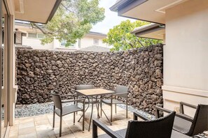 Uma área de pátio com muro de pedra, mesa e cadeiras.