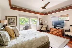 Quarto com cama, televisão, penteadeira e obras de arte nas paredes.