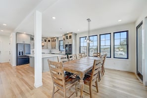 A spacious kitchen with a central island, wooden dining table, and chairs.