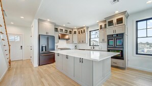 Una cocina moderna con una isla central, electrodomésticos integrados y un amplio ventanal que proporciona luz natural.