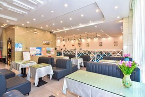 A restaurant interior with booths, tables, and a decorative vase. - Shun Xing Hotel (Dali City)