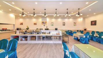 Un salón de conferencias con una larga mesa, sillas y una zona de cocina.