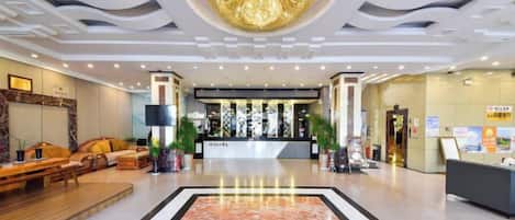 A hotel lobby with a reception desk, seating area, and a large decorative ceiling feature.
