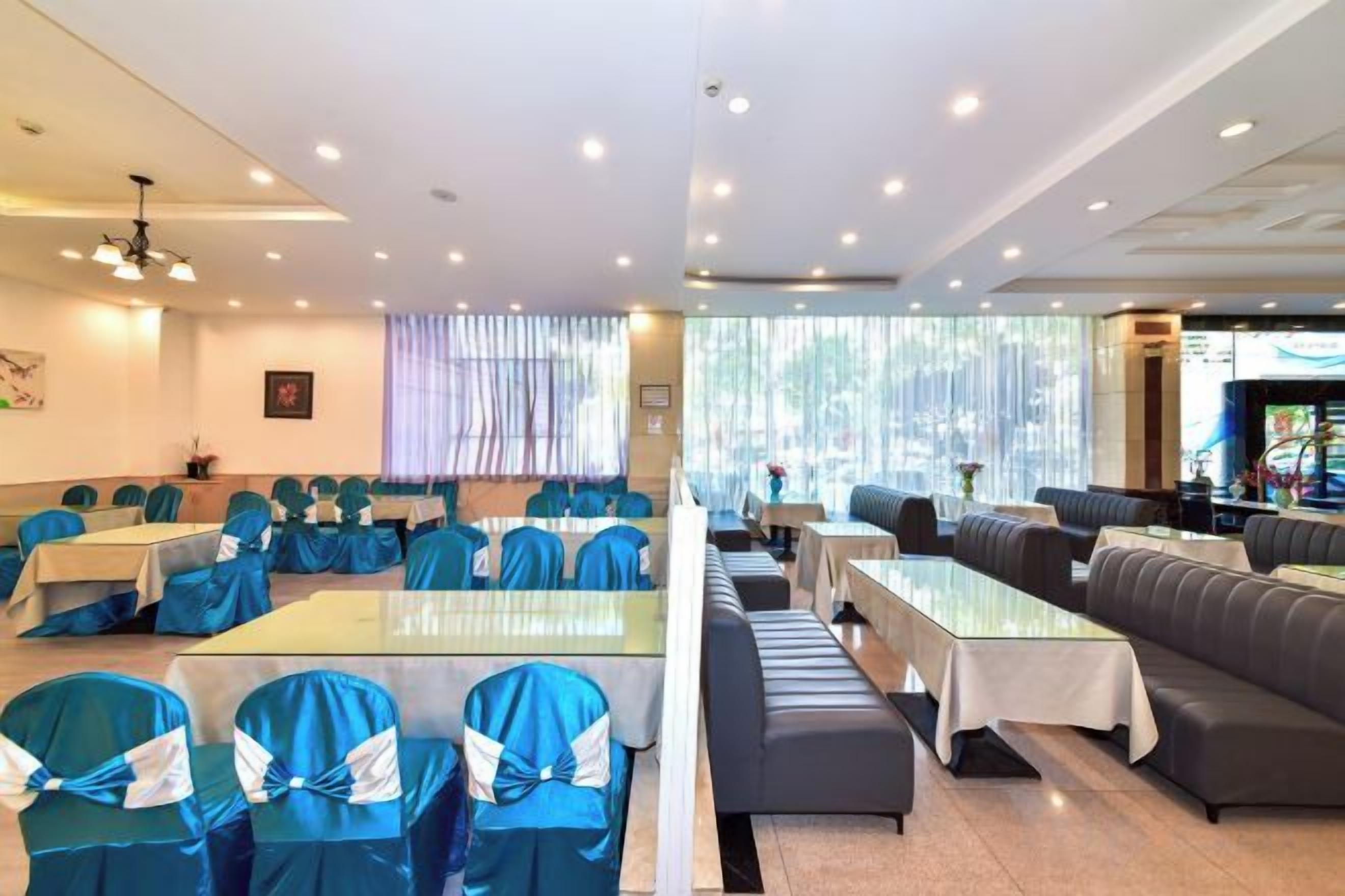 Uma área de refeições de hotel com mesas, cadeiras, um balcão comprido e um espaço de estar com sofás.