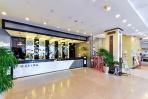 A hotel lobby with a reception desk, a staircase, and potted plants. - Shun Xing Hotel (Dali City)