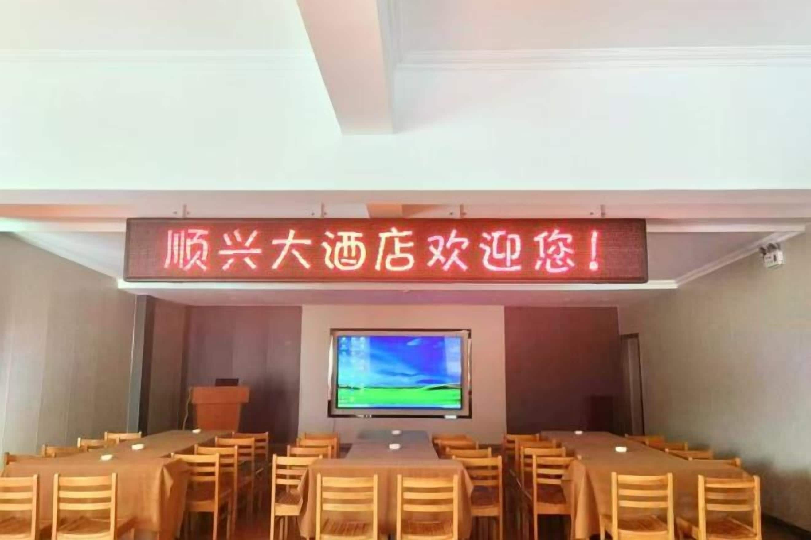 Un salón de conferencias con una pantalla grande, varias mesas y sillas dispuestas para reuniones.