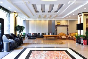 A hotel lobby with a reception desk, seating area with sofas and chairs, a large coffee table, and a flat-screen TV mounted on the wall. - Shun Xing Hotel (Dali City)