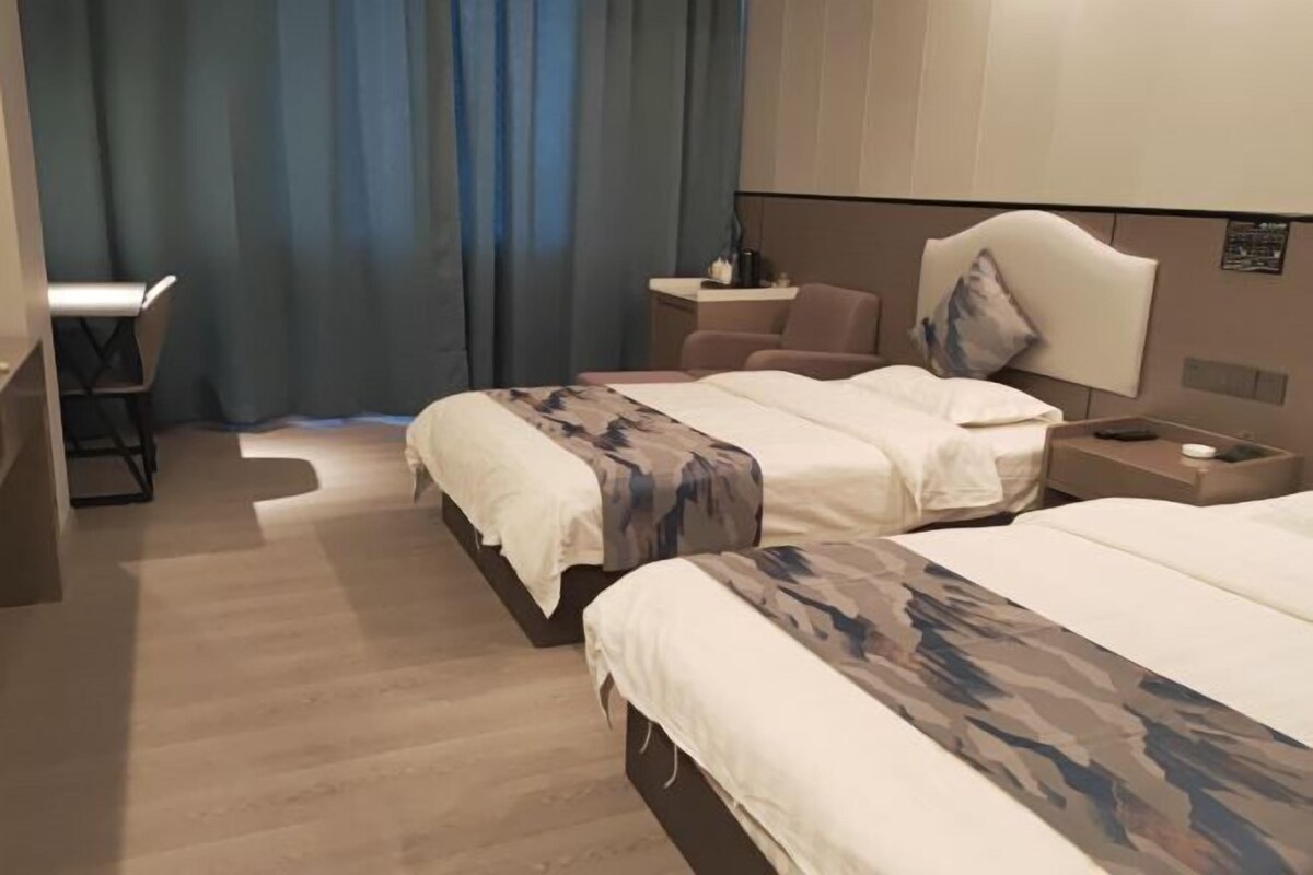 Ein Hotelzimmer mit zwei Betten, einem Schreibtisch und einem Stuhl.