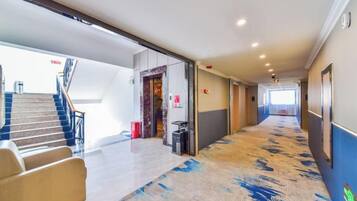 Un pasillo de hotel con piso alfombrado, una escalera y una recepción.