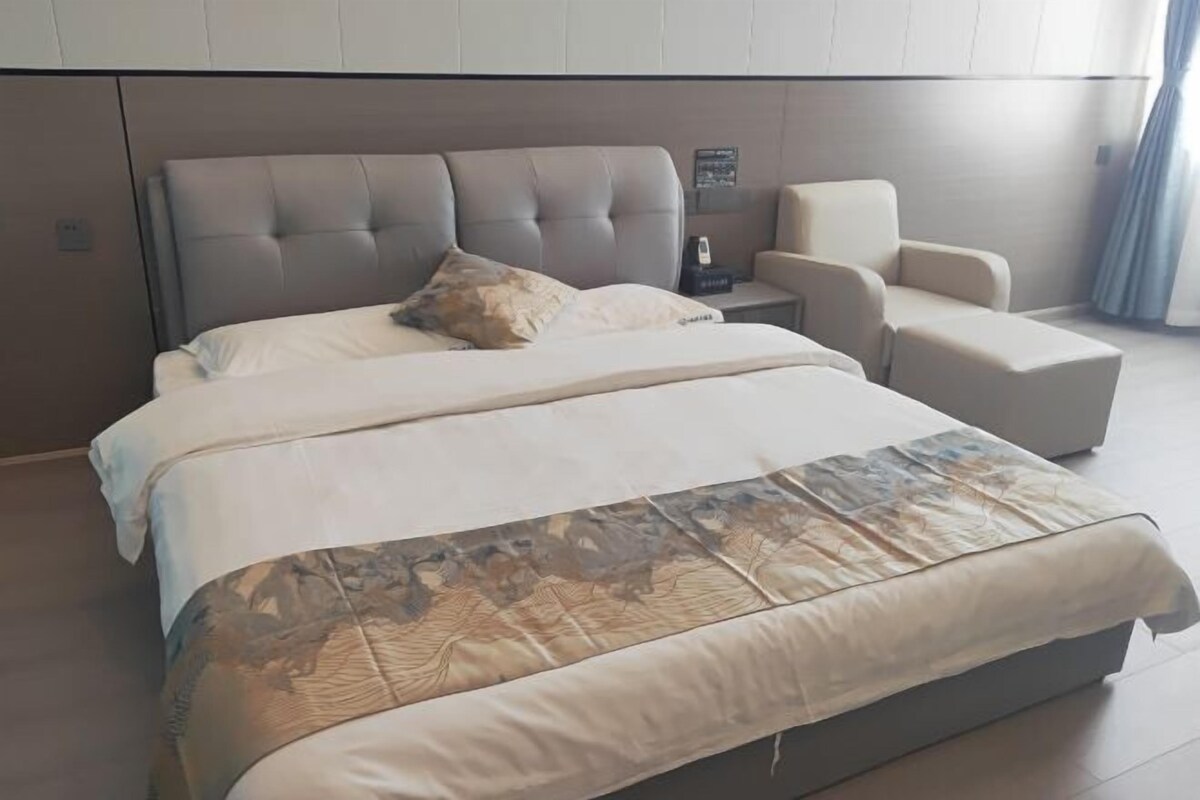 Ein modernes Schlafzimmer mit einem großen Bett, einem Nachttisch und einer Sitzecke.
