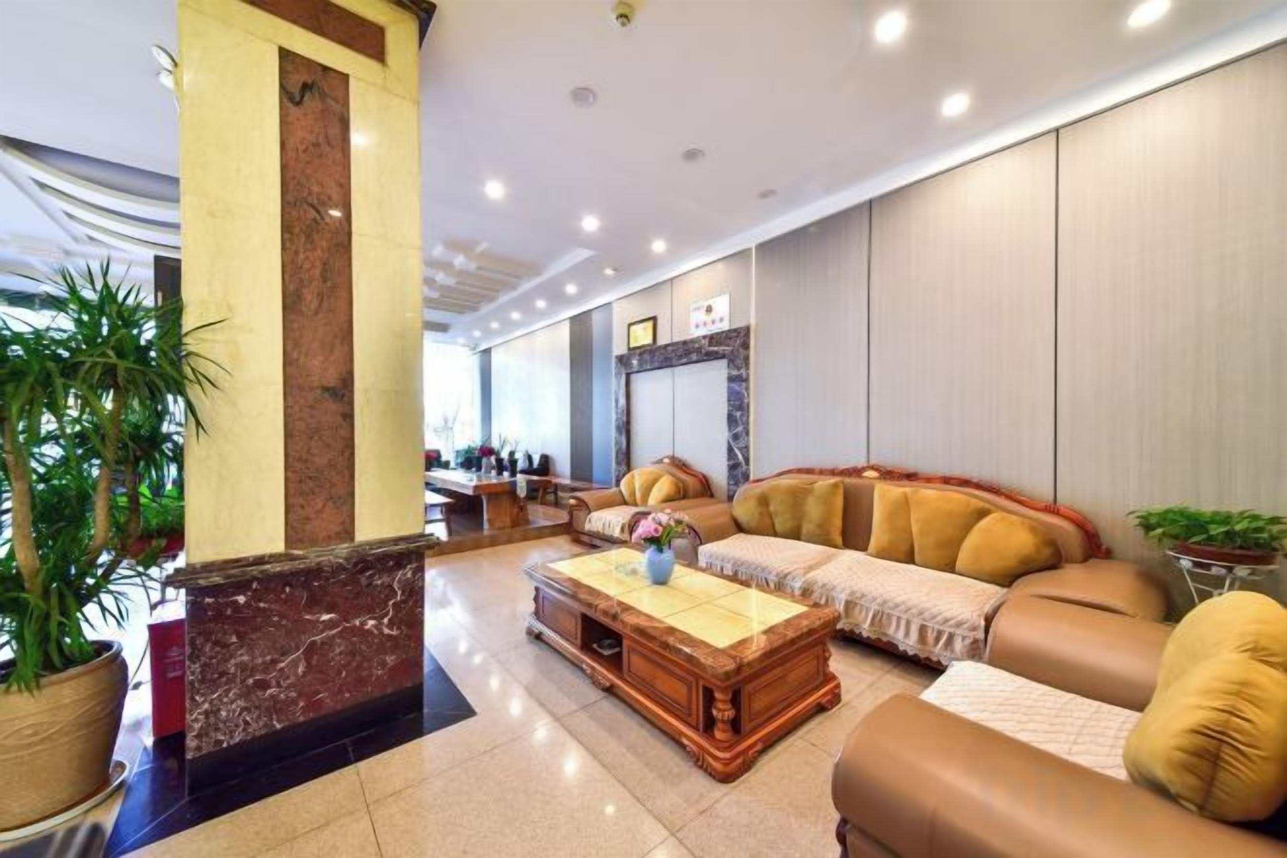 A lobby with a reception desk, seating area, and a large plant.