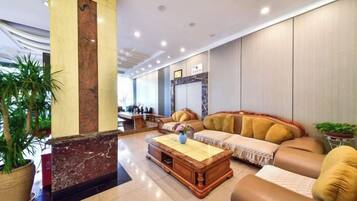 A lobby with a reception desk, seating area, and a large plant.