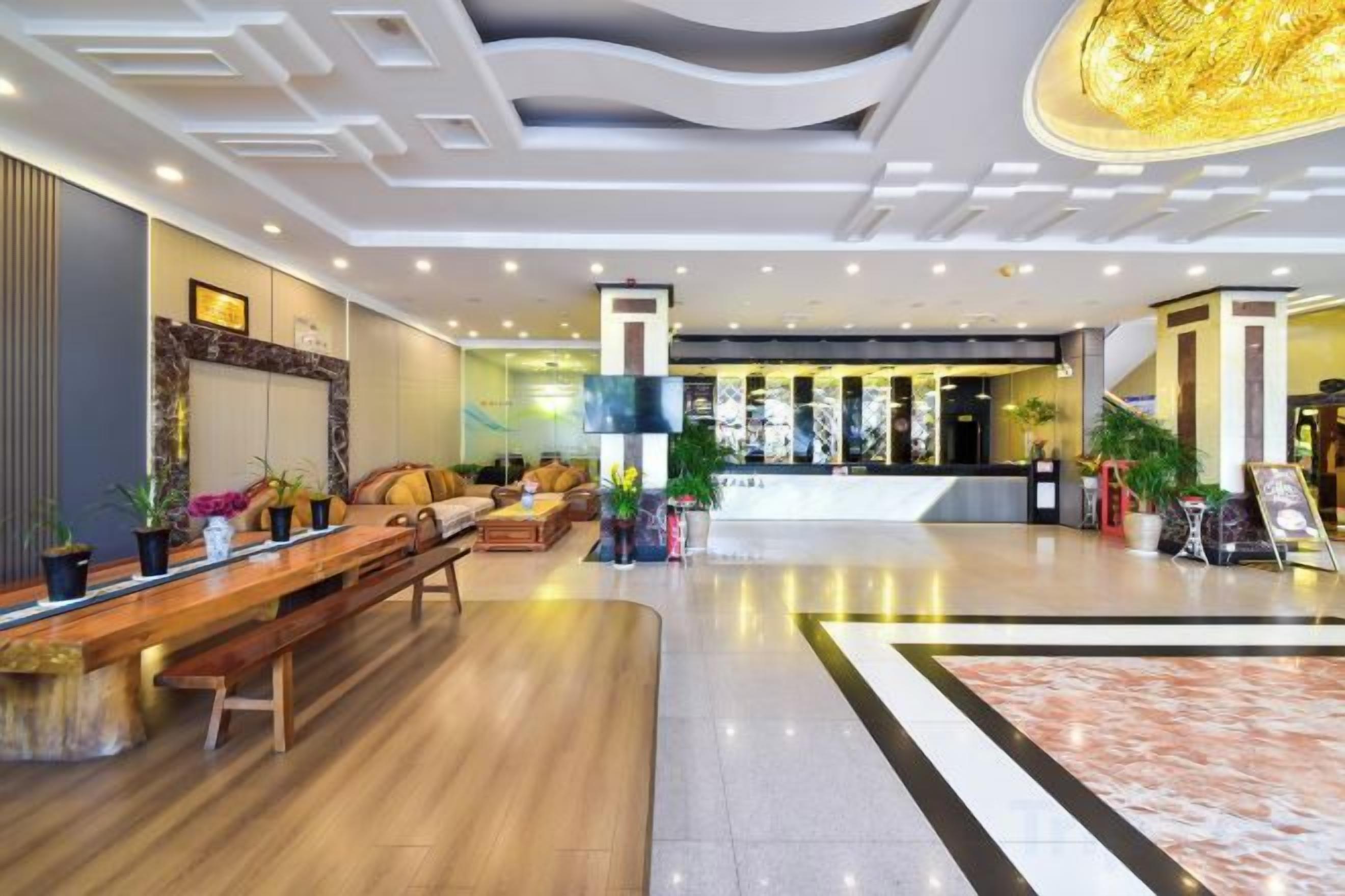 Um lobby moderno com balcão de atendimento, área de estar e um grande candelabro.
