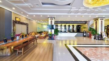Um lobby moderno com balcão de atendimento, área de estar e um grande candelabro.
